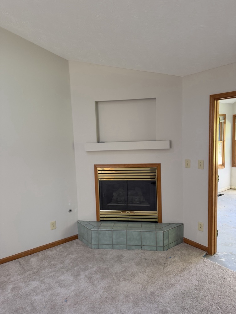 Before: corner fireplace with brass trim and green tile hearth