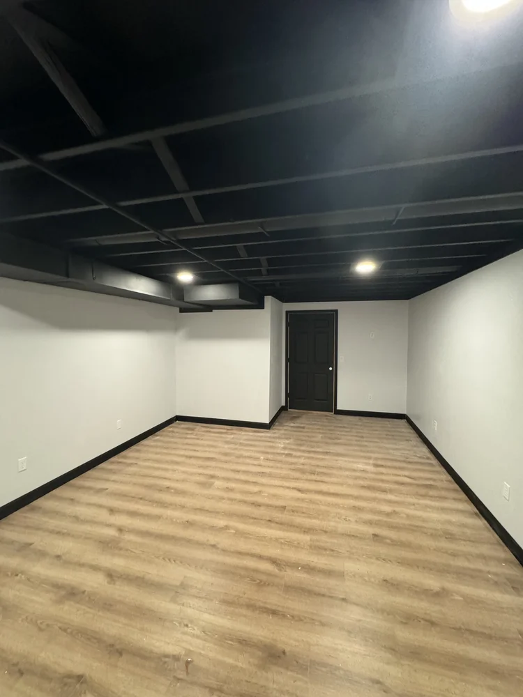 Finished basement with new flooring and black ceiling