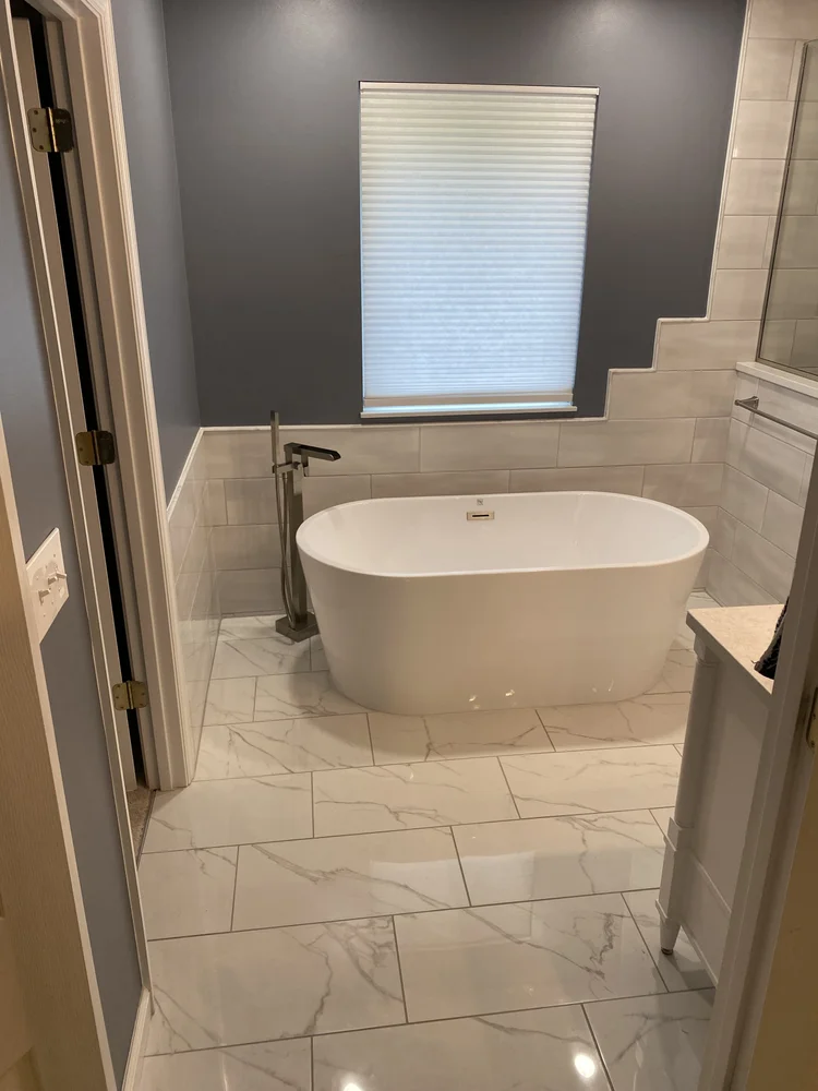 Bathroom with white freestanding tub and marble tile floor