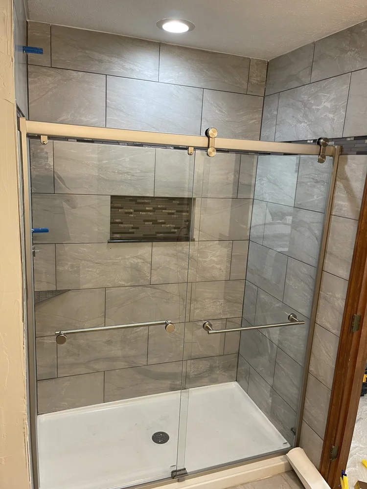 Walk-in shower with gray stone tile and built-in niche